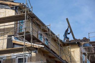 A contractor moves roofing material on a home under construction in San Ramon in January. Joe Mathews says rent control isn’t going to solve California’s housing shortage.